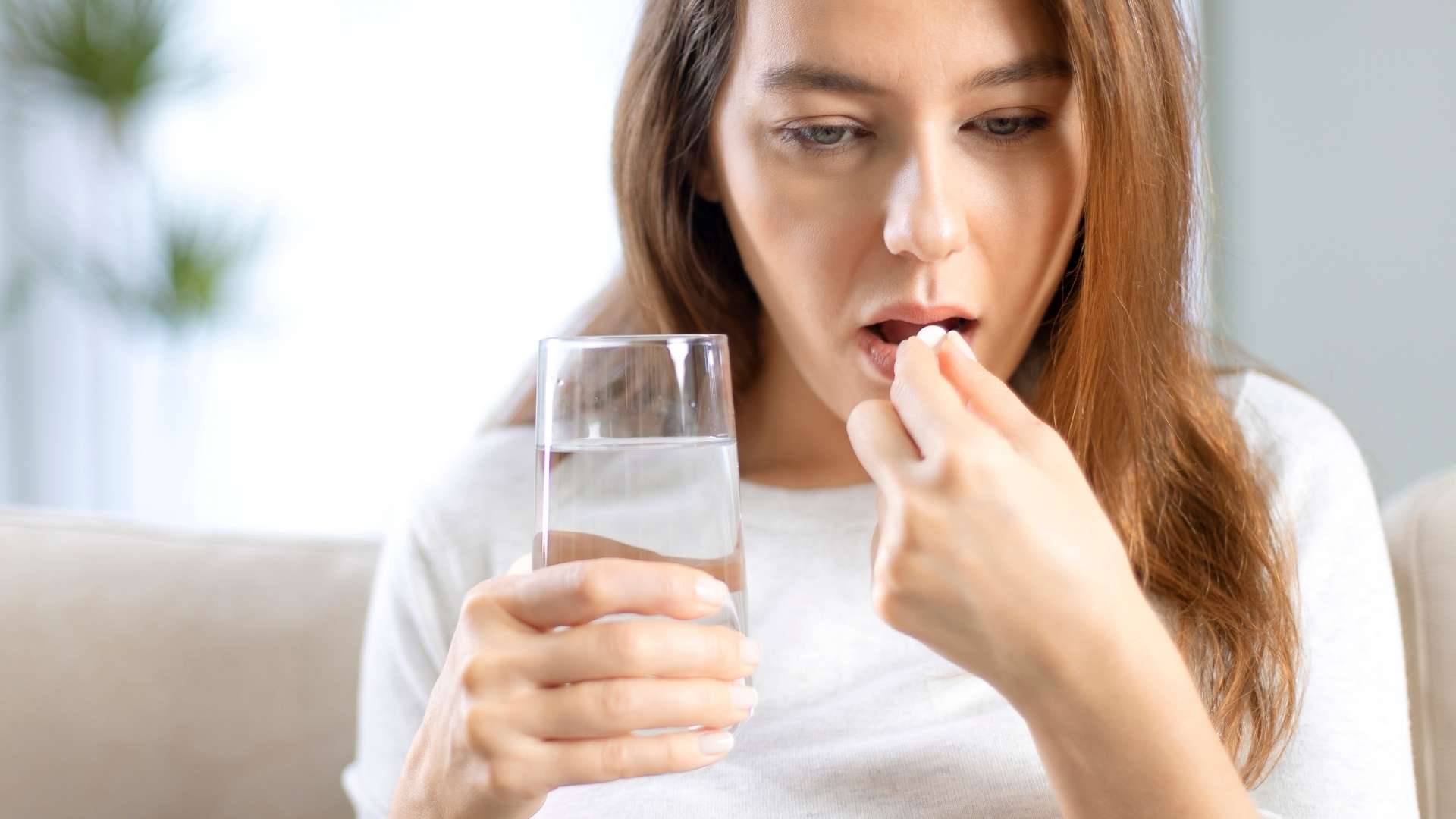 A woman swallows an oral hormone replacement therapy pill