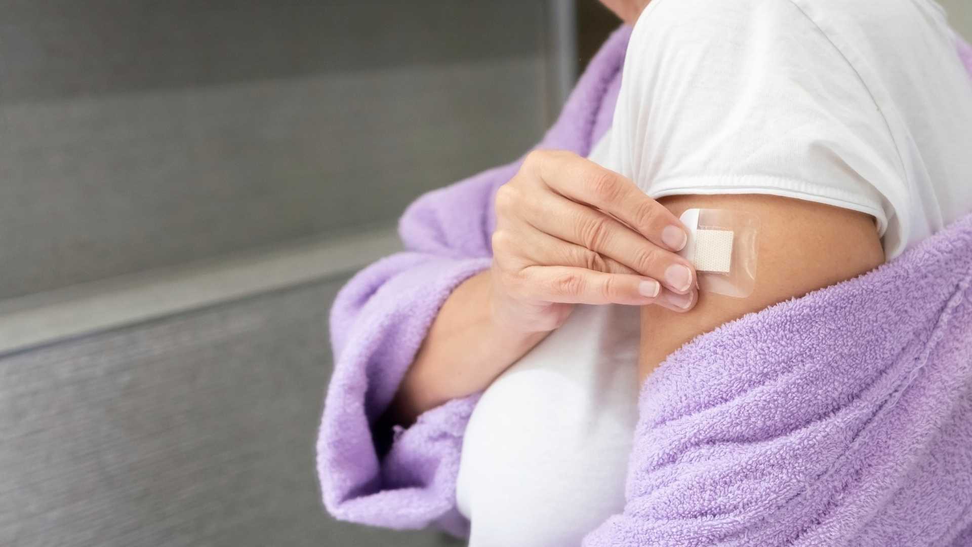 A woman puts a patch on her arm
