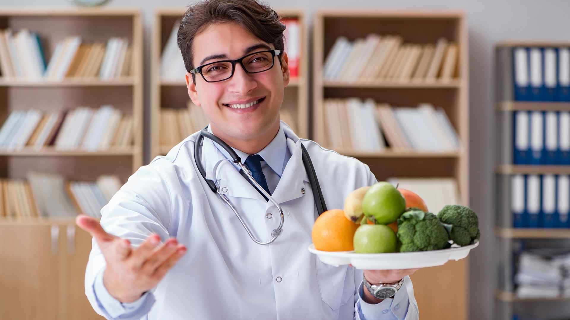 A doctor holds a bowl of fruit and vegetables