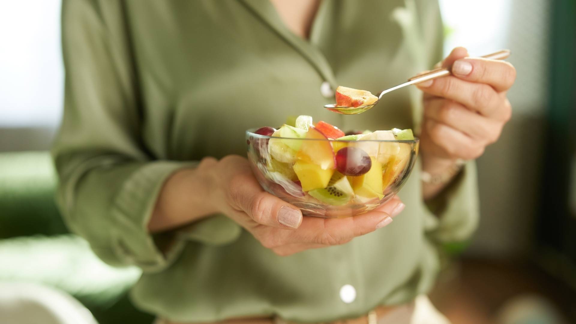 Someone eats a bowl of fruit salad