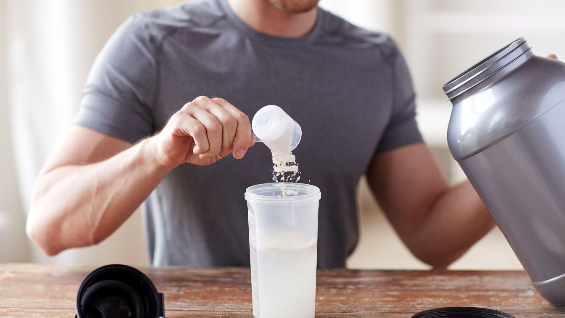 A person puts a scoop of creatine into their protein shaker