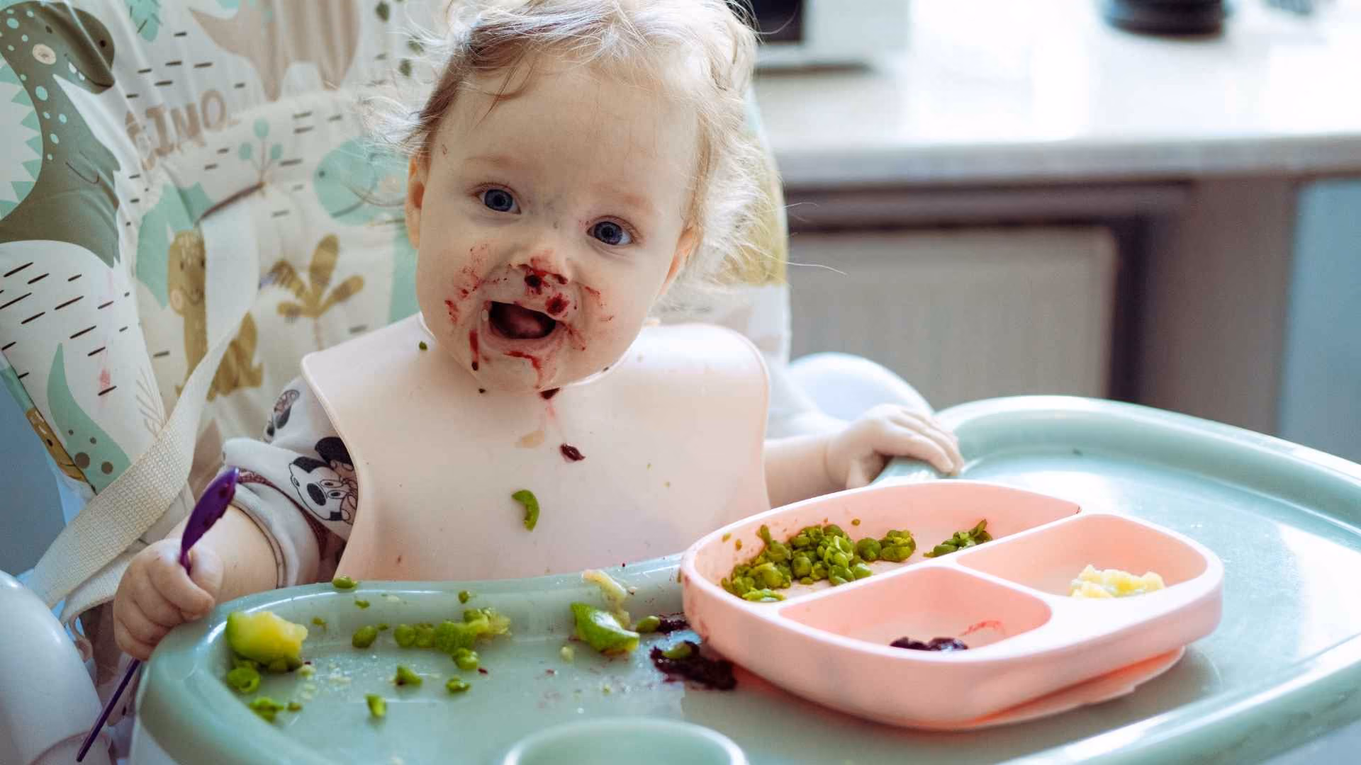 A baby eats some vegetables