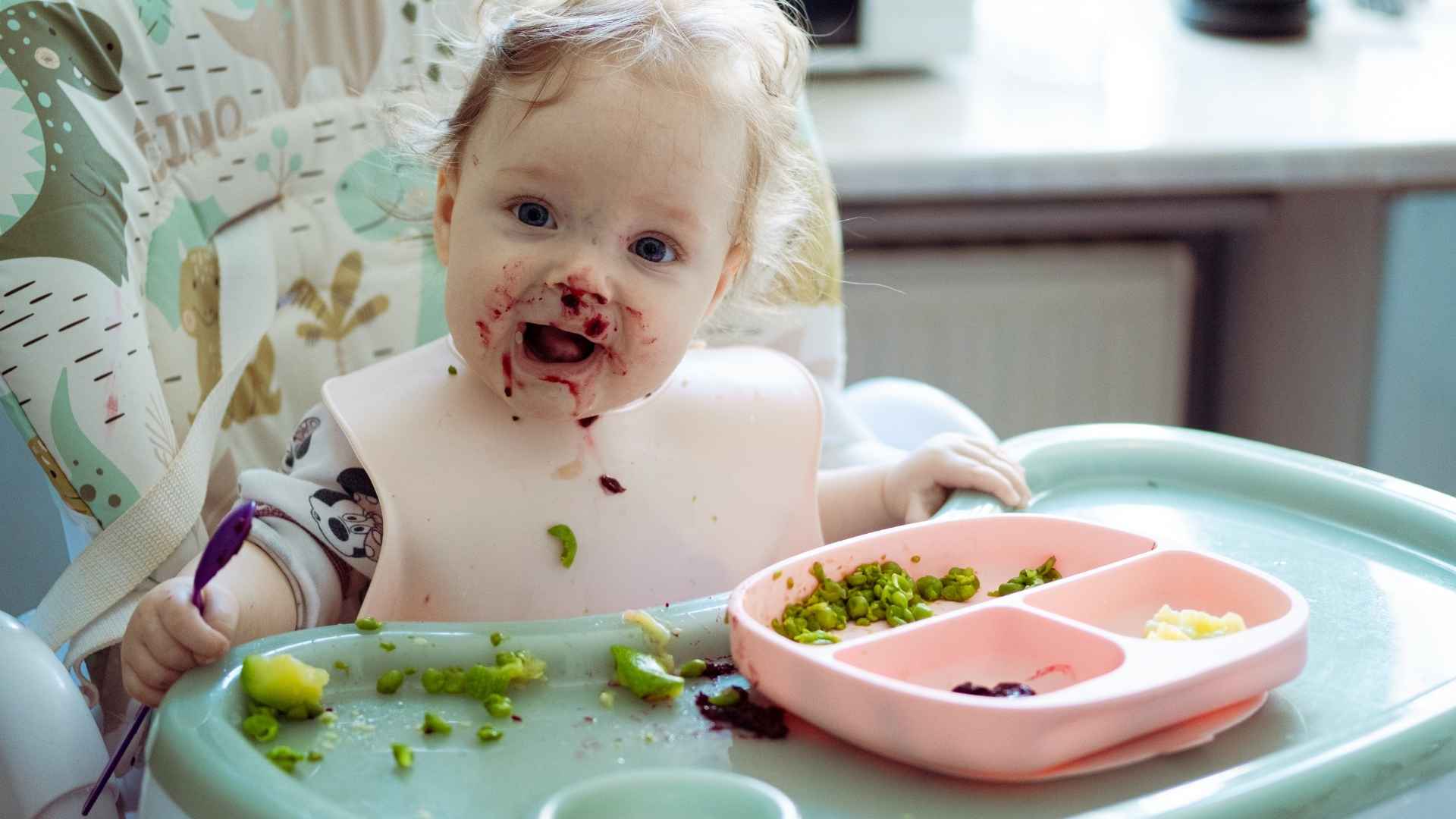 A baby eats some vegetables