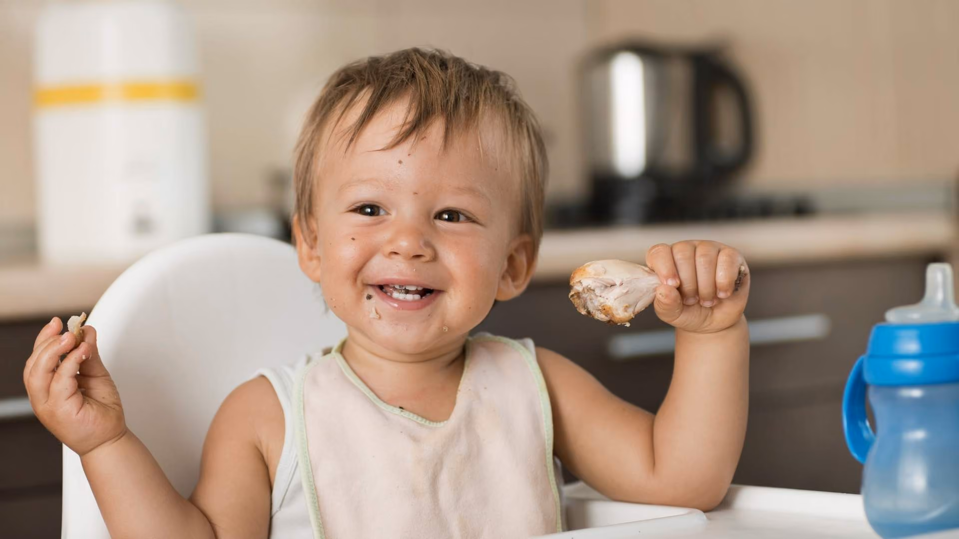 A baby eats some chicken