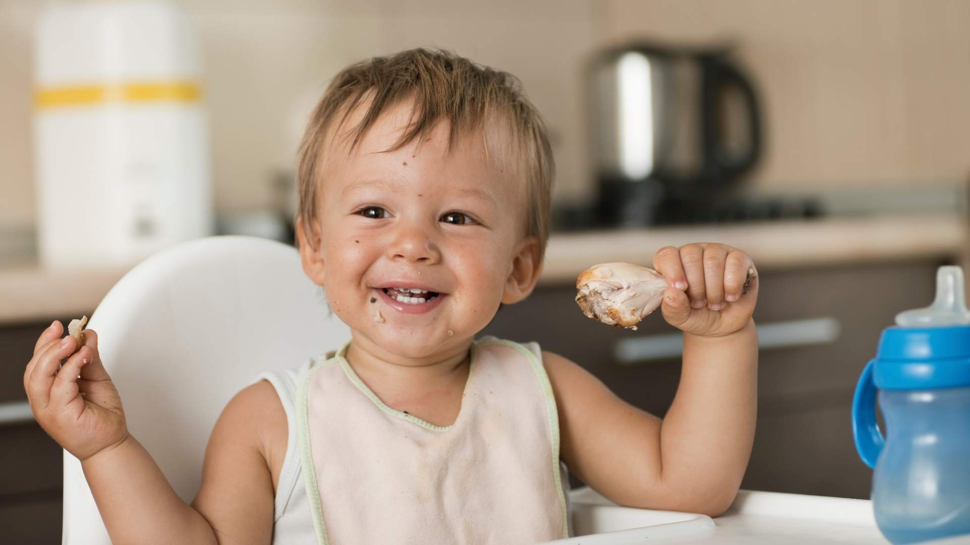 A baby eats some chicken