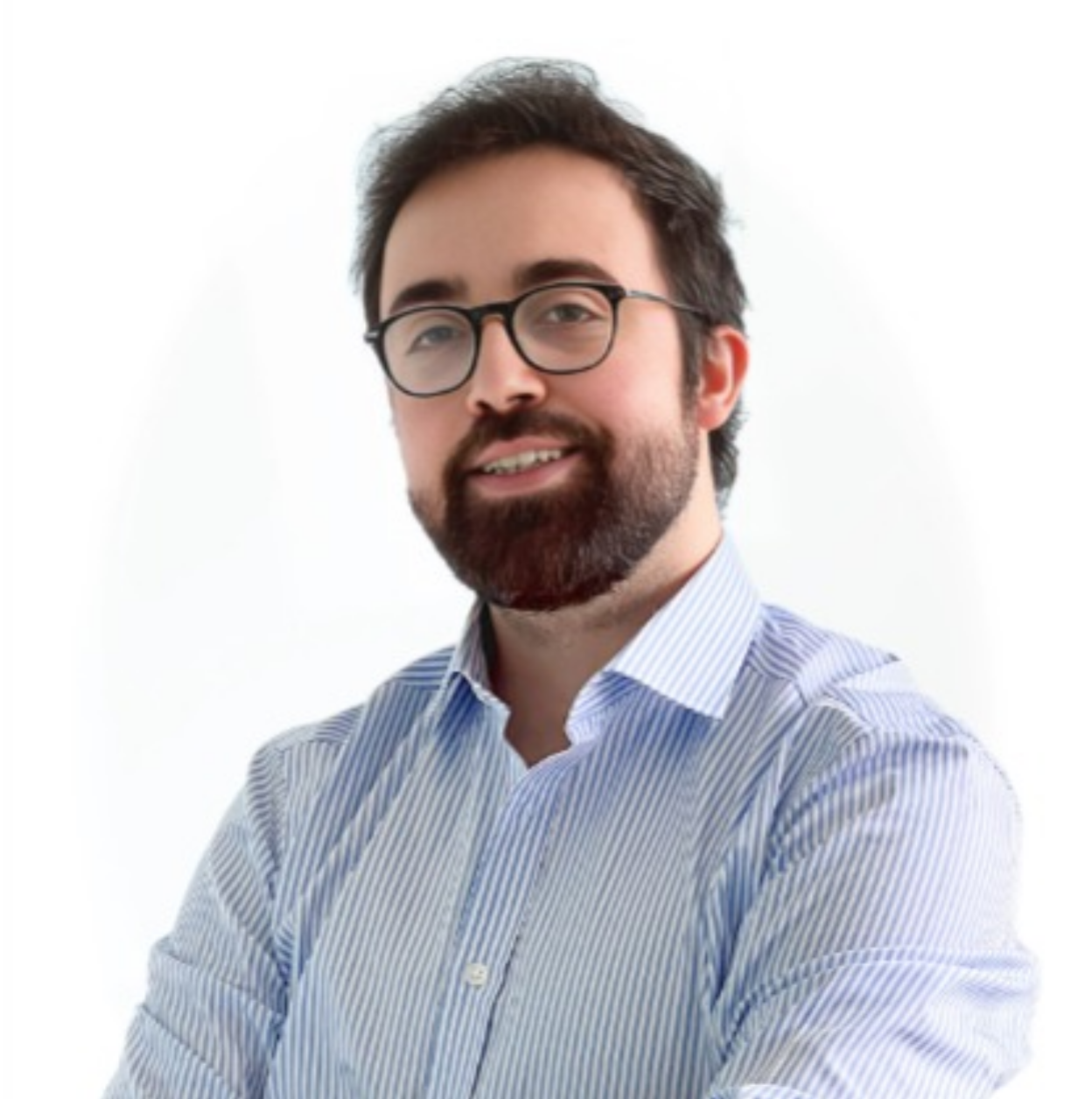 Homme souriant avec barbe et lunettes, portant une chemise rayée bleue et blanche.