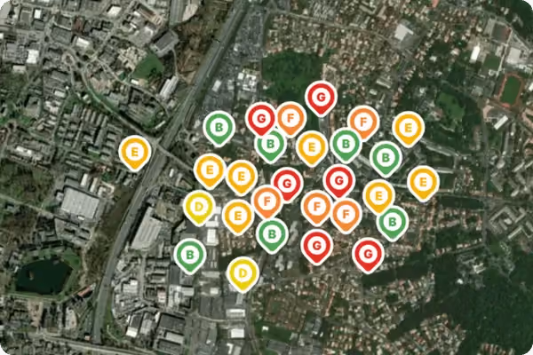 Carte satellite d'une zone urbaine avec des marqueurs colorés indiquant des classes énergétiques variées de bâtiments, allant de B à G.