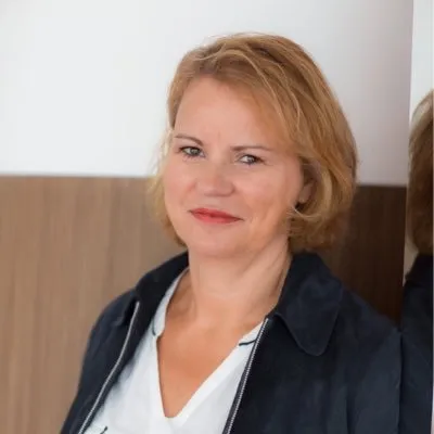 Portrait professionnel d'une femme blonde en veste sombre.