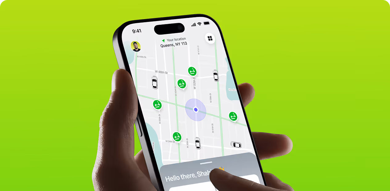 Hand holding a smartphone showing a map with location pins and nearby cars in Queens, NY by Wavespace.