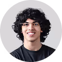 Young man with curly black hair, wearing a black shirt, smiling against a light gray circular background.