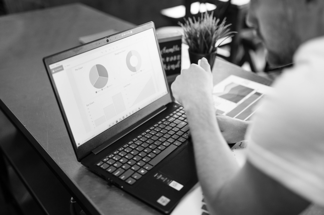 A man is looking at carts and graphs displayed on a laptop.
