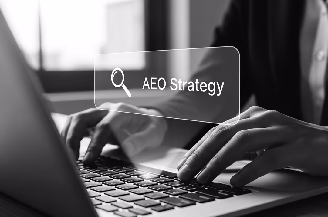 A search bar with the phrase "AEO Strategy" hovers over hands typing on a laptop.