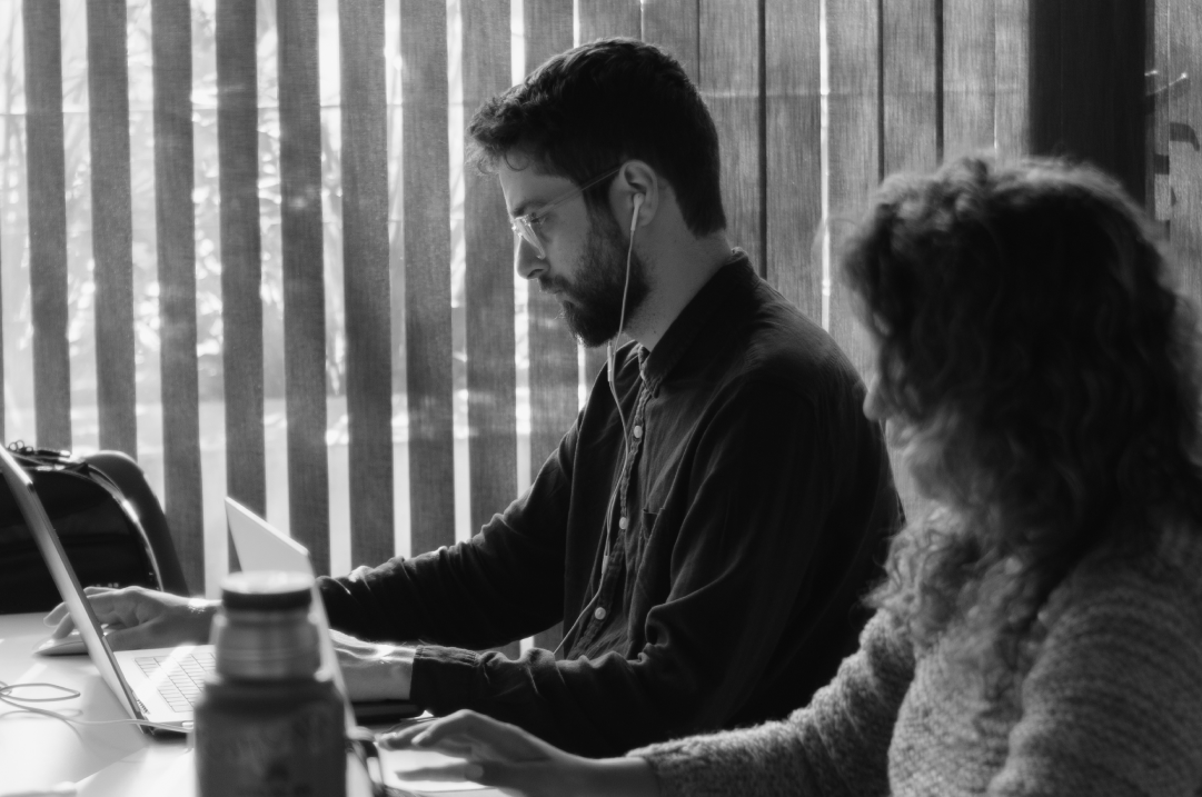 A man and a woman work next to each other on laptops.