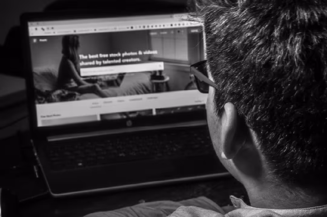 A person wearing glasses is looking at a website on a laptop.