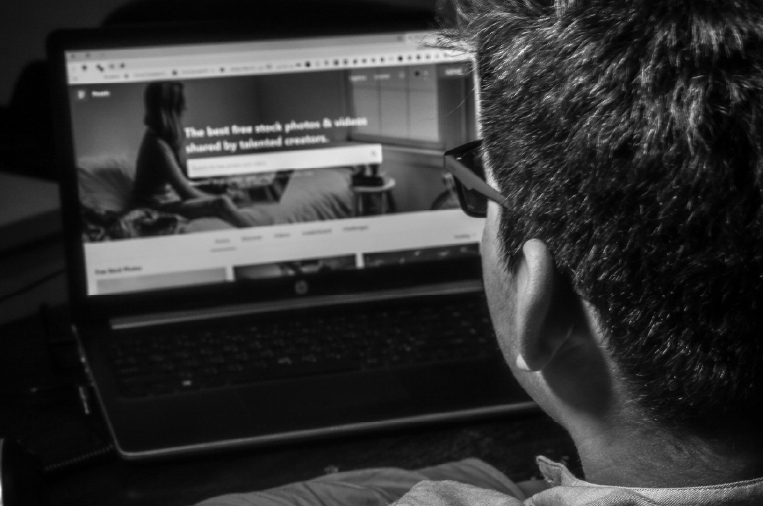 A person wearing glasses is looking at a website on a laptop.