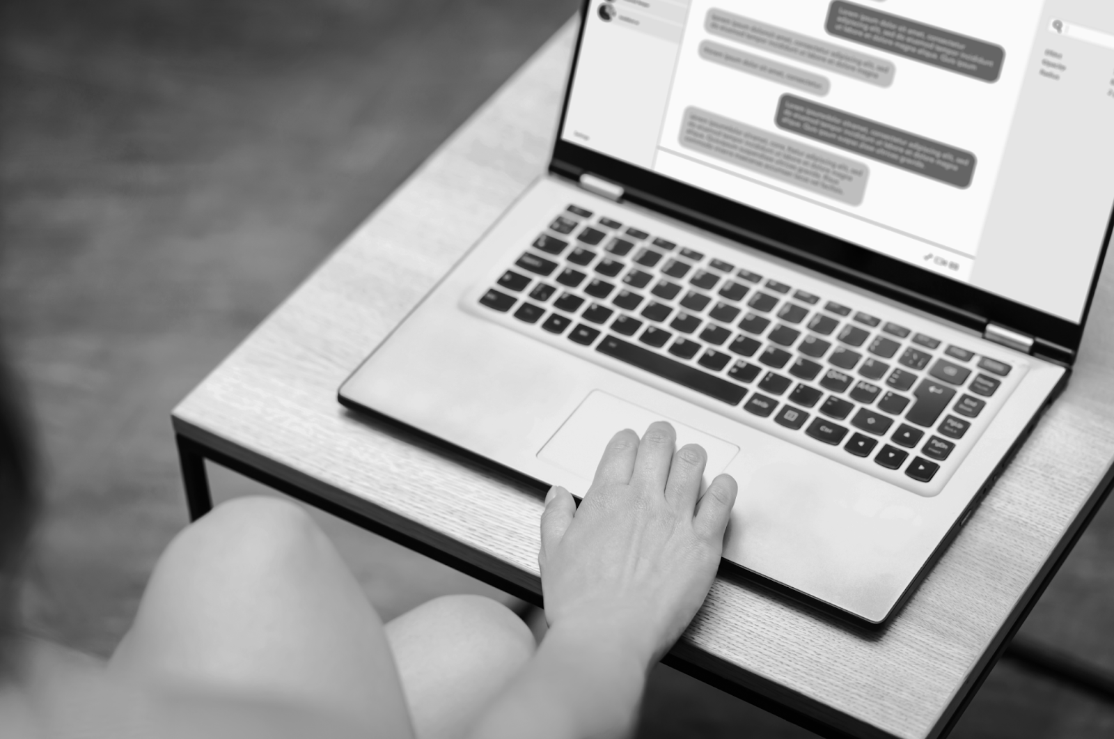 A hand rests on a laptop that is displaying a chat exchange.