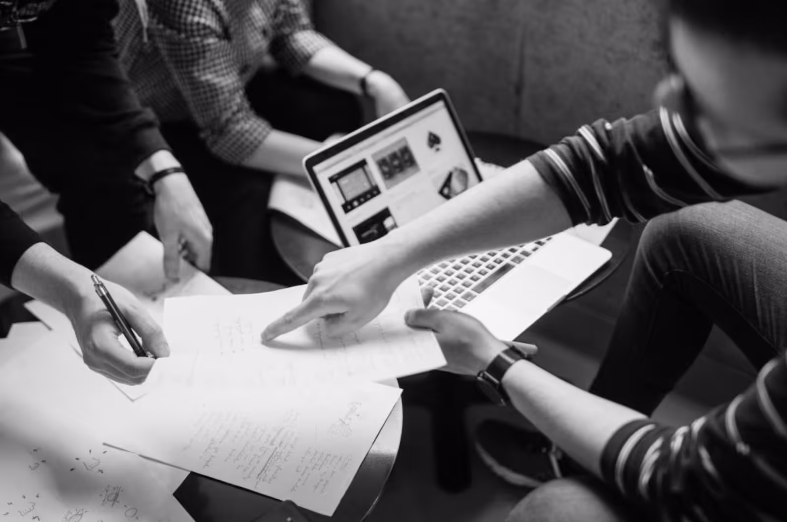 Three people are reviewing documents in a workspace.