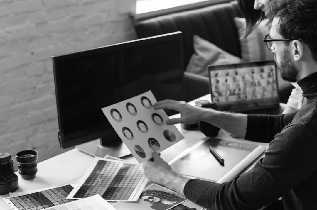 Designer reviewing brand color palettes and visual concepts on a computer desk.