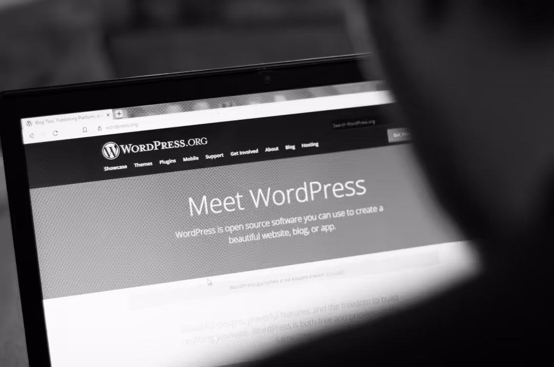 A laptop displays the Wordpress homepage.