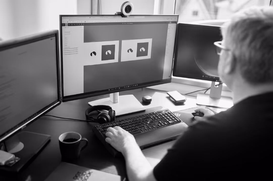 A person sits in an office chair looking at a pair of images on a monitor.