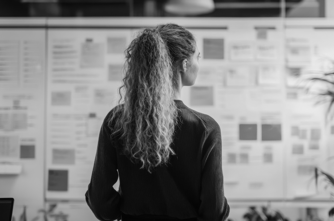 Woman analyzing brand strategy frameworks for tech companies on a wall filled with research notes, competitive analysis, and UX planning boards.