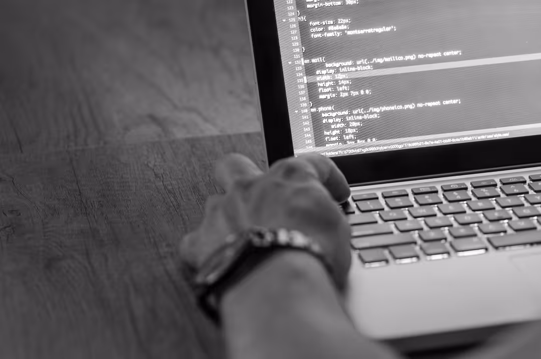 A hand enters lines of code onto a laptop.