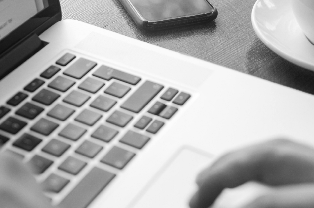 A closeup of fingers touching the keyboard of a laptop.