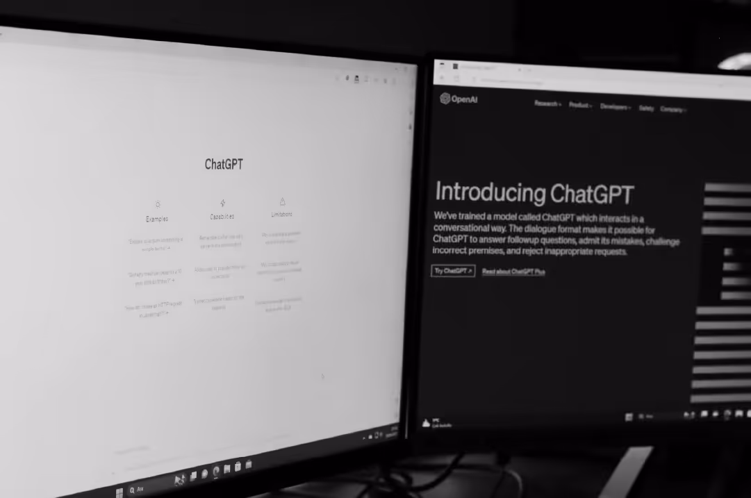 Two monitors display different pages from the ChatGPT website.