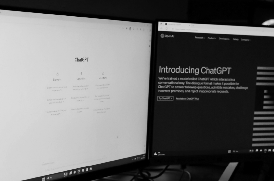 Two monitors display different pages from the ChatGPT website.