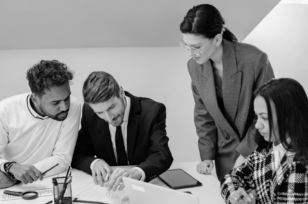 A group pf people examine a document on an office table.