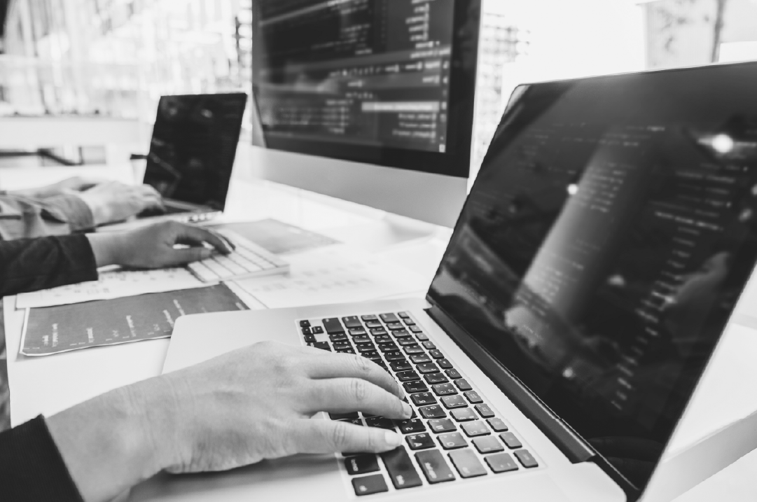 Three people's hands are shown typing on the keyboards of their computers.
