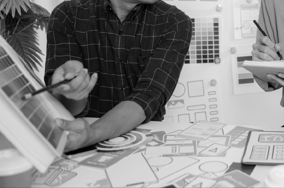 A man points to a page in a book while a person standing next to him takes notes.