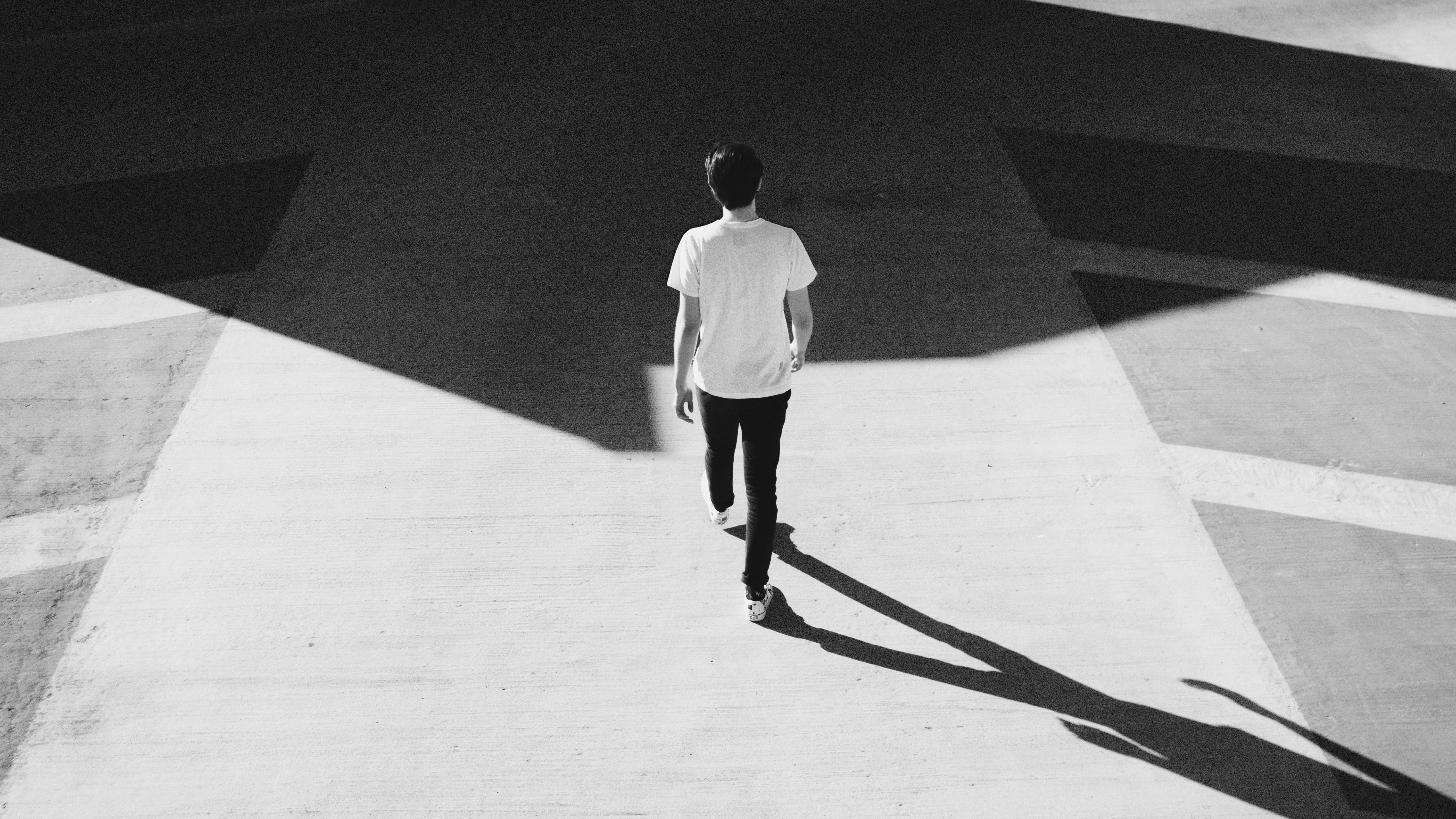 Aerial view of a person walking alone on a geometric black and white surface, symbolizing the first steps of SaaS user onboarding-