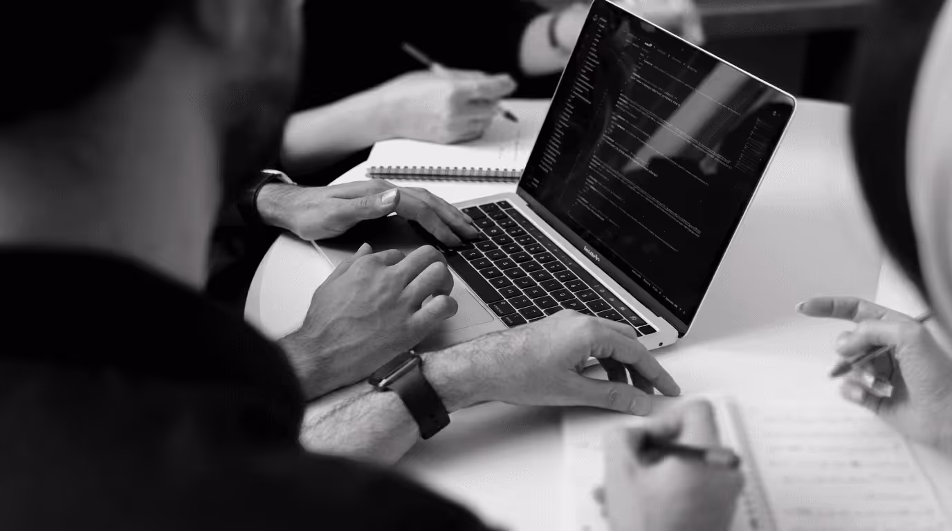 B2B tech team reviewing app development code together on a laptop