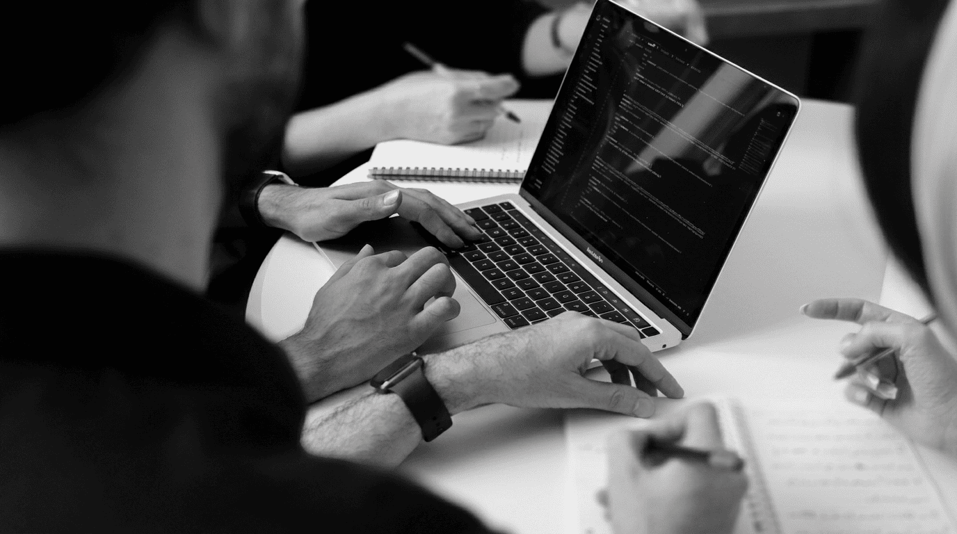 B2B tech team reviewing app development code together on a laptop