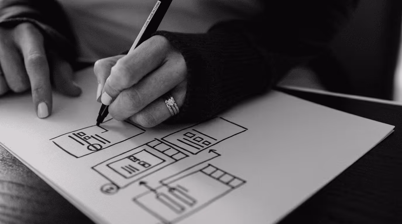 Designer sketching SaaS product interface wireframes on paper.