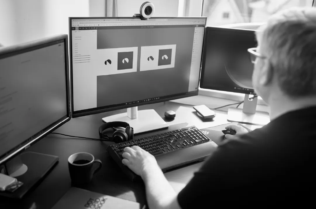 Designer working on SaaS brand interface components across multiple monitors.