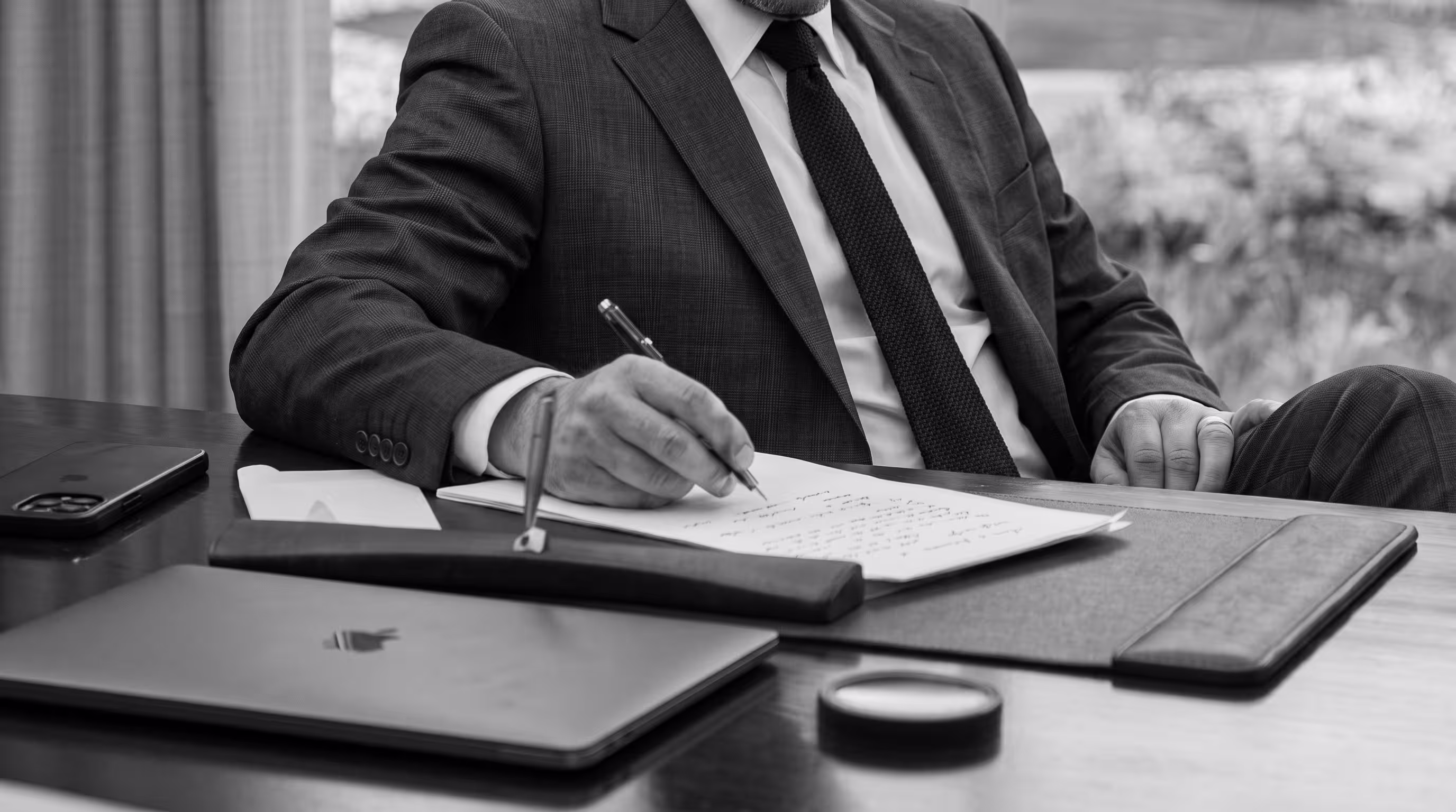 Black and white photo of a person handwriting notes at a desk