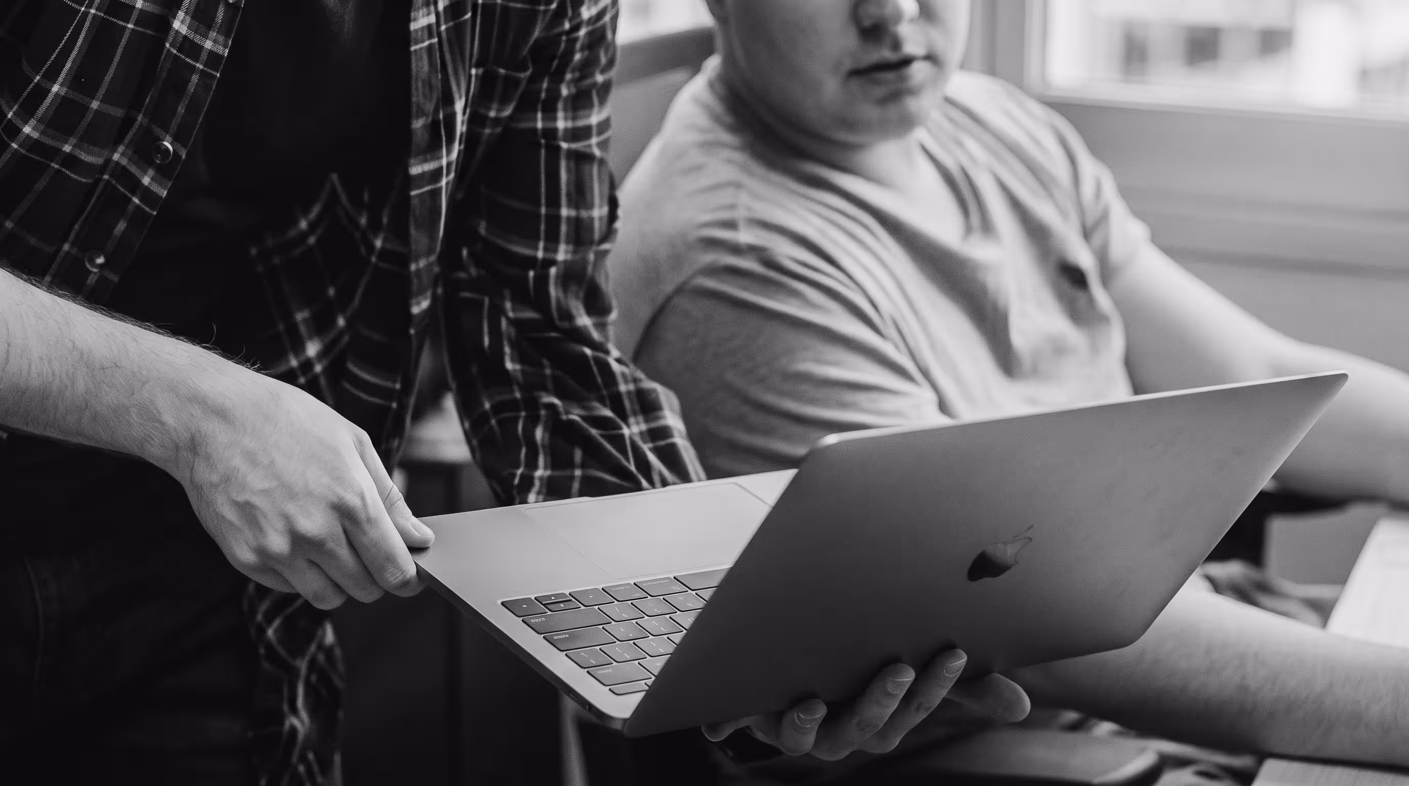 Black and white photo of two people reviewing a laptop together