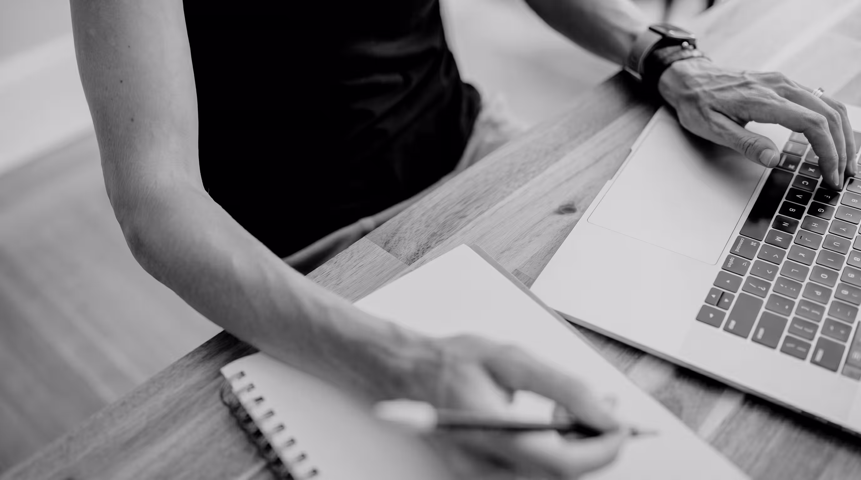 Black and white overhead photo of two people working at a desk