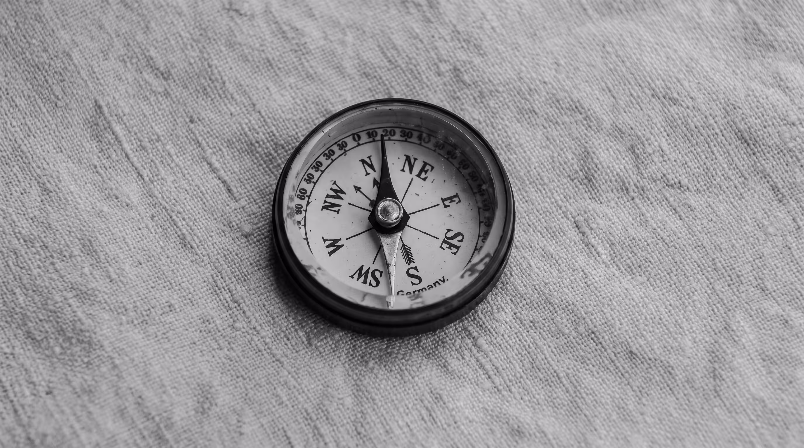Close-up of an old compass on woven fabric, black and white