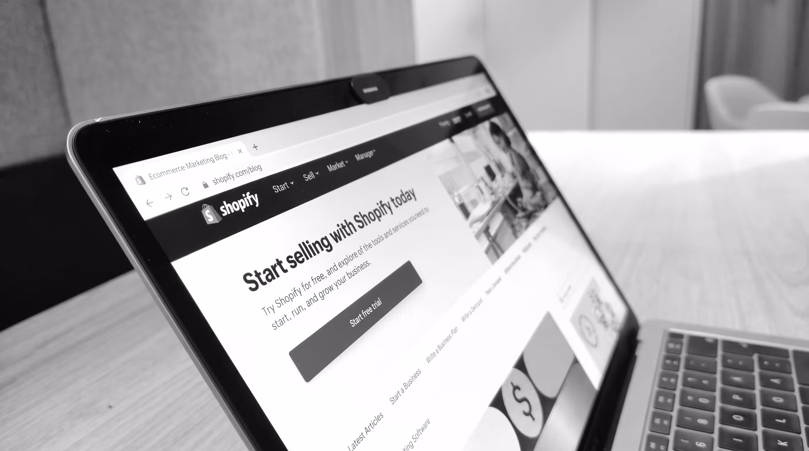 Black and white photo of the Shopify website on a laptop screen