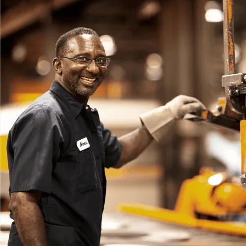 A working man, smiling and fist bumping someone else.