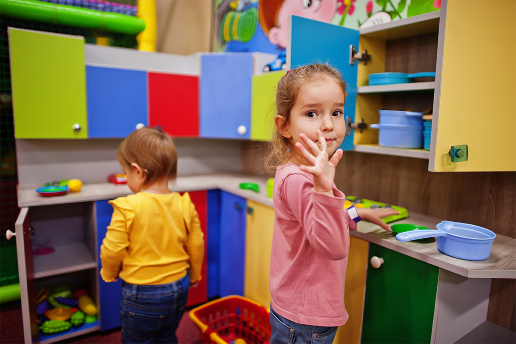 Two small children are playing in a toy kitchen at a child care center