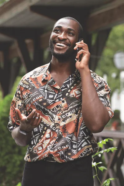 Man in a colourful shirt holding a phone to his ear