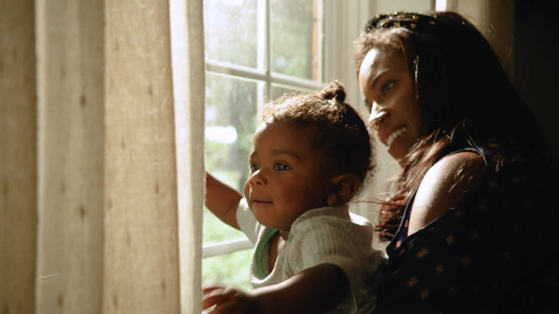 A mother and small child looking out the window.