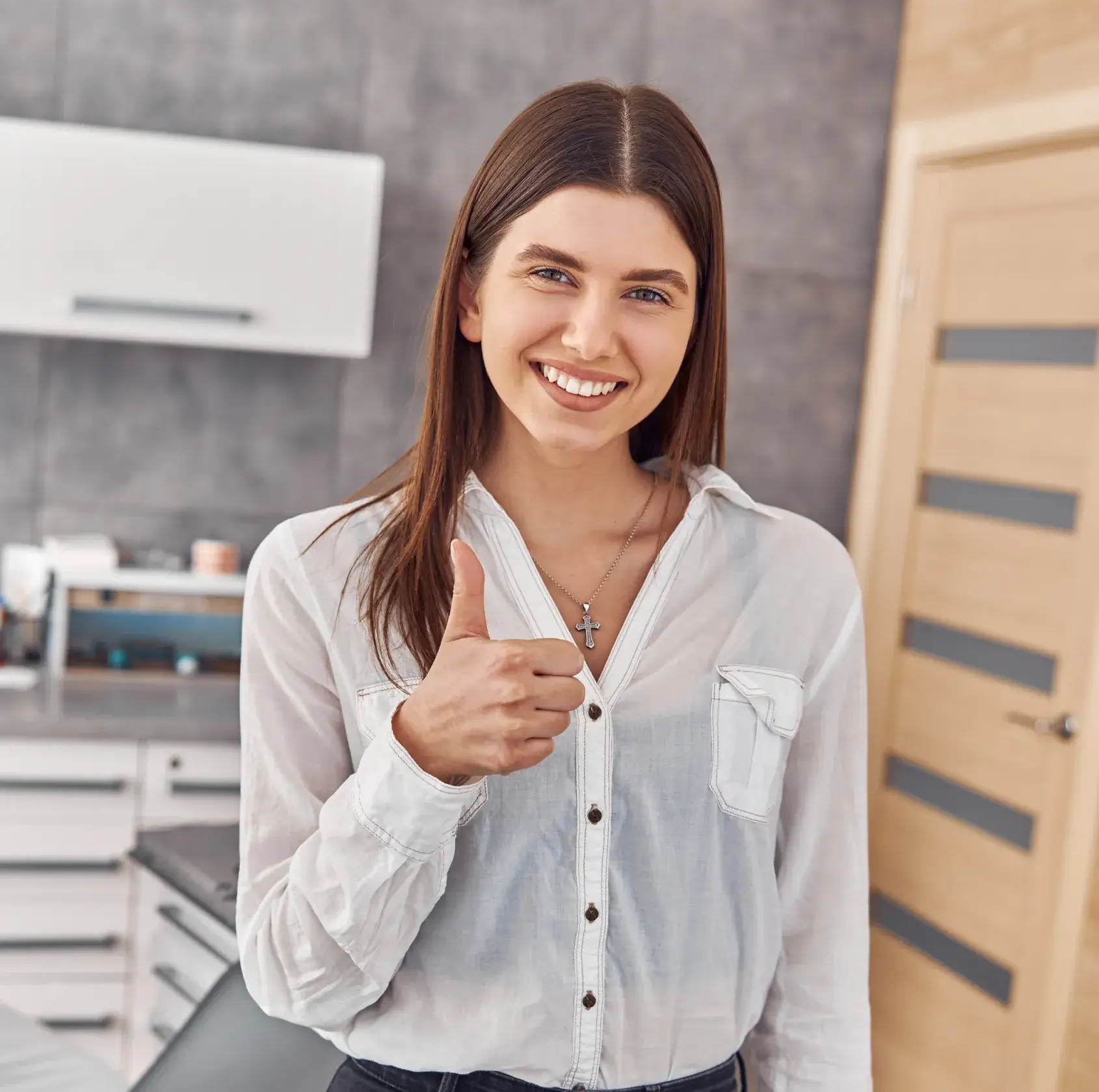 A woman giving a thumbs up in a kitchen.