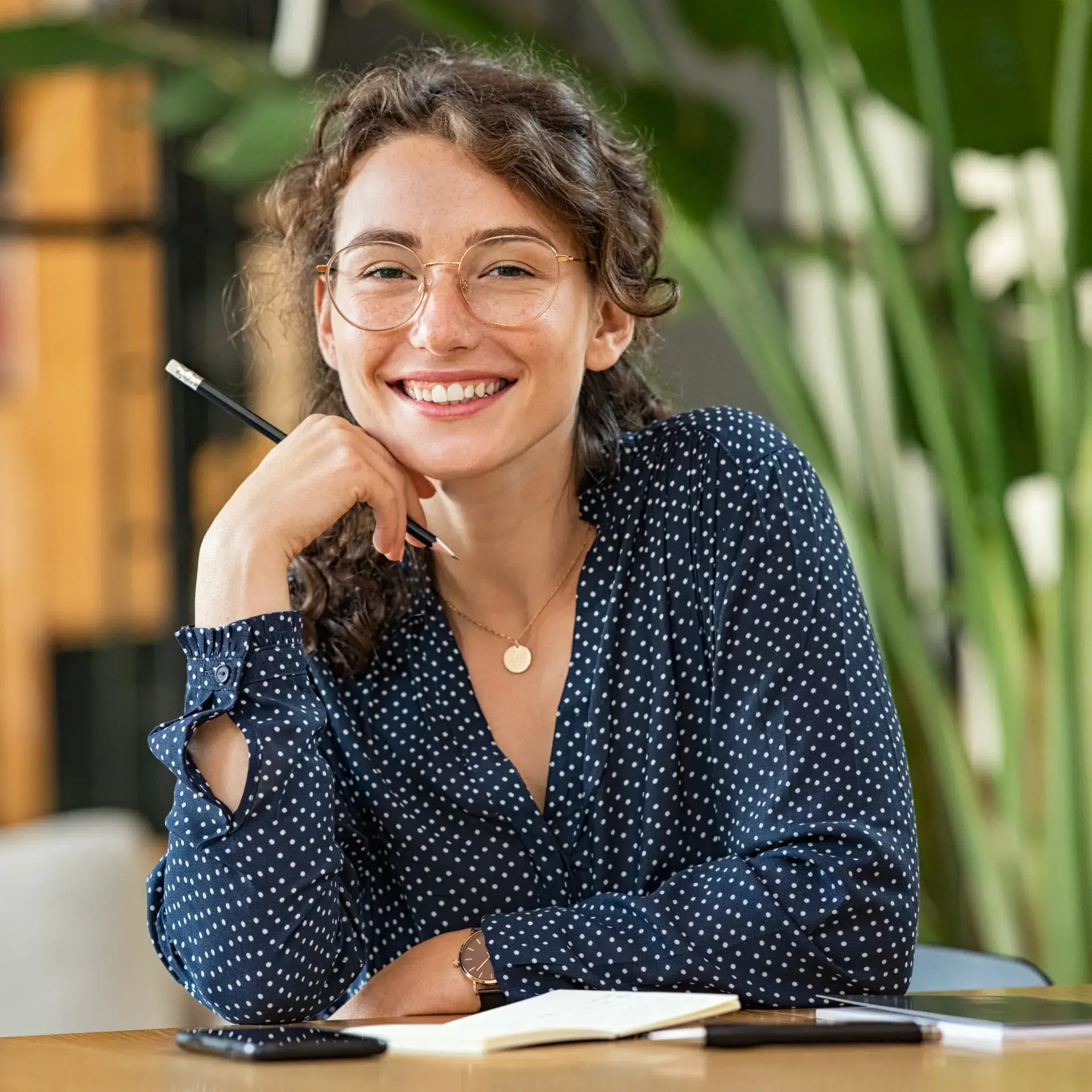 A woman sitting at a table with a pen in her hand.