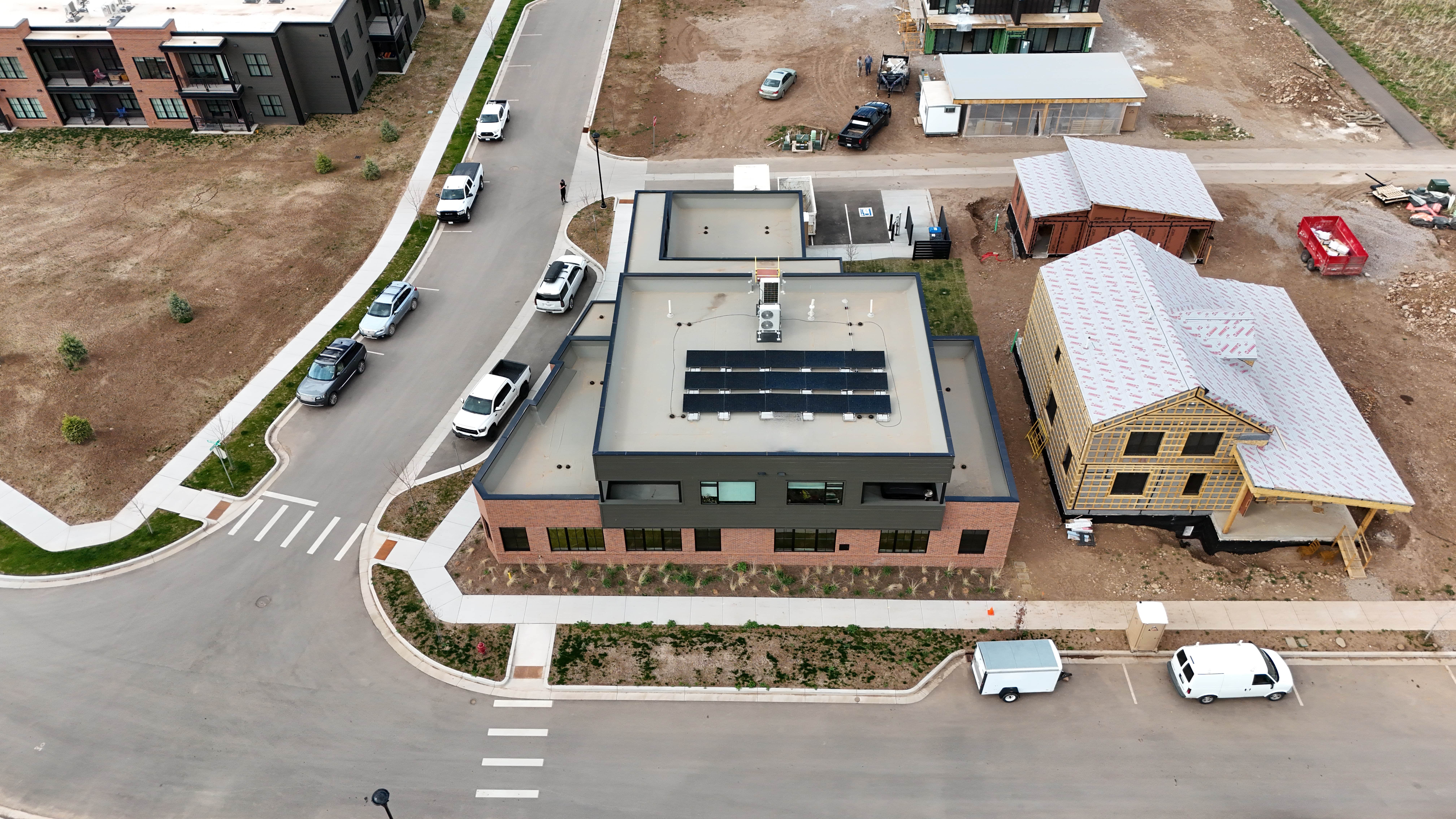 Aerial view of the Basalt Daycare building with solar panels on its flat roof, beside a new wood-framed building