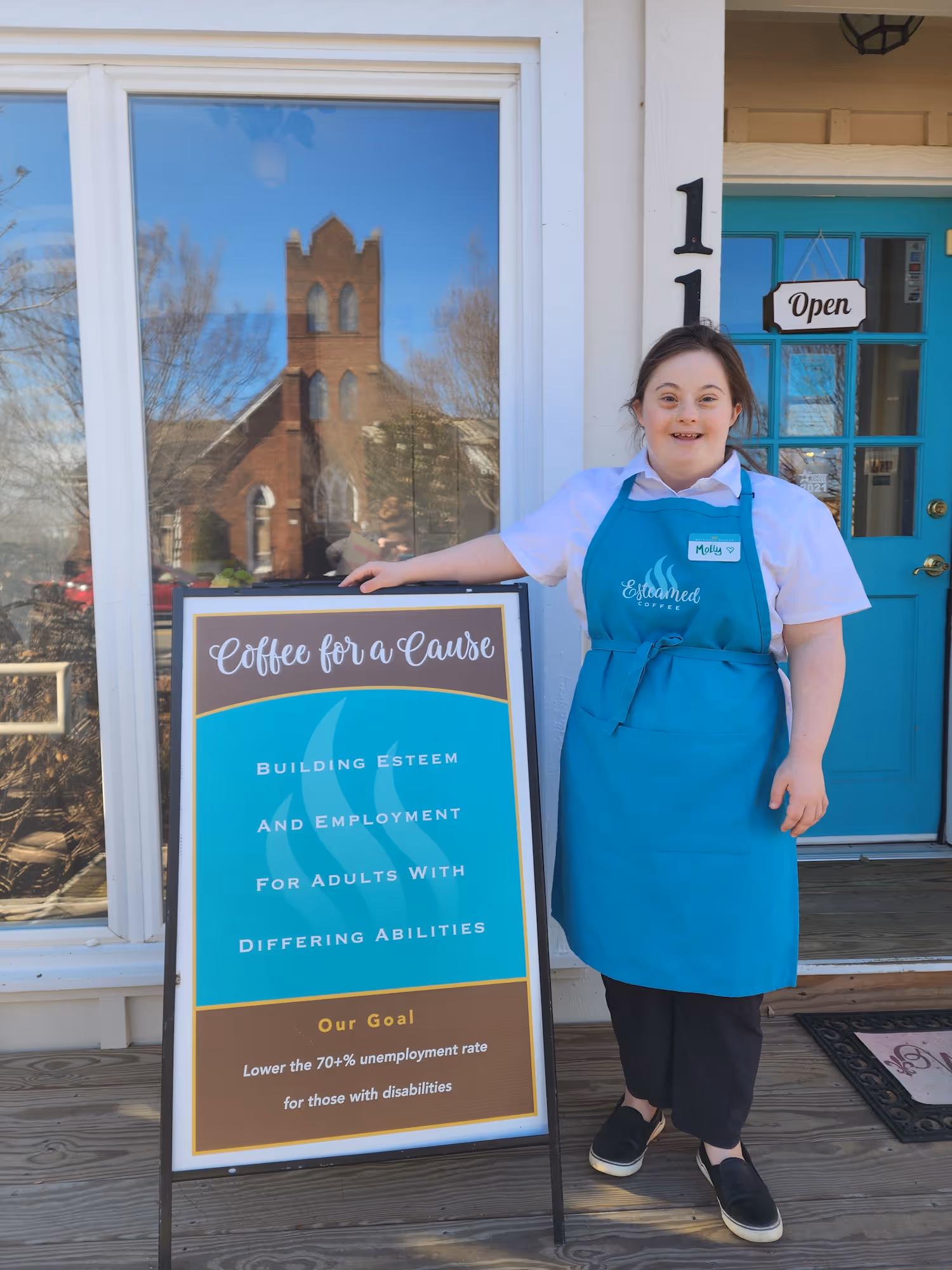 Barista Molly standing outside in front of the shop smiling